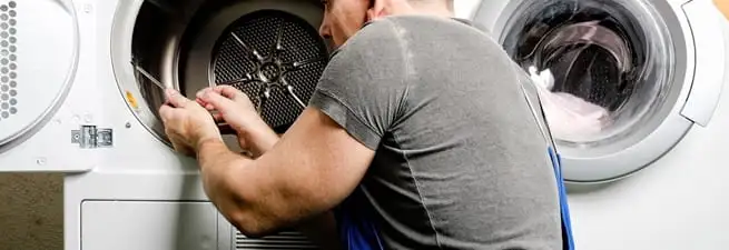 Dryer repair technician fixing a clothes dryer drum in Omaha, NE