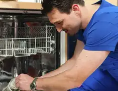Dishwasher repair technician inspecting and servicing an open dishwasher in Omaha, NE