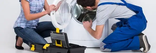 Washer repair technician inspecting a front-load washing machine with tools in Omaha, NE