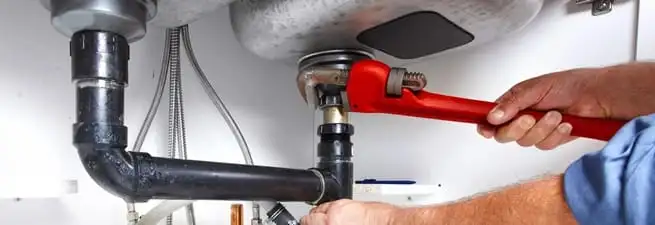 Garbage disposal repair technician tightening the sink drain and disposal connection in Omaha, NE