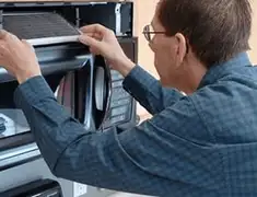 Appliance repair technician replacing a microwave vent filter in Omaha, NE