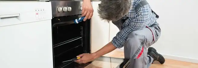 Oven repair technician inspecting and servicing an electric oven in Omaha, NE