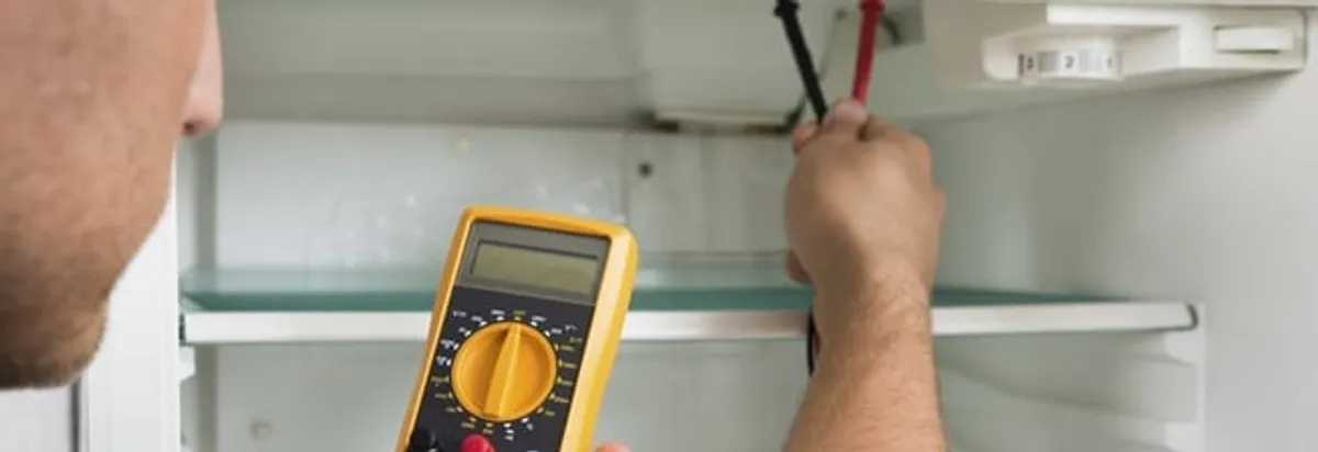 Refrigerator repair technician testing electrical components with a multimeter in Omaha, NE