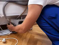 Appliance repair technician fixing refrigerator water line and connections in Omaha, NE