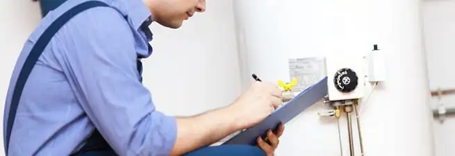 Water heater repair technician inspecting the unit and recording service notes in Omaha, NE